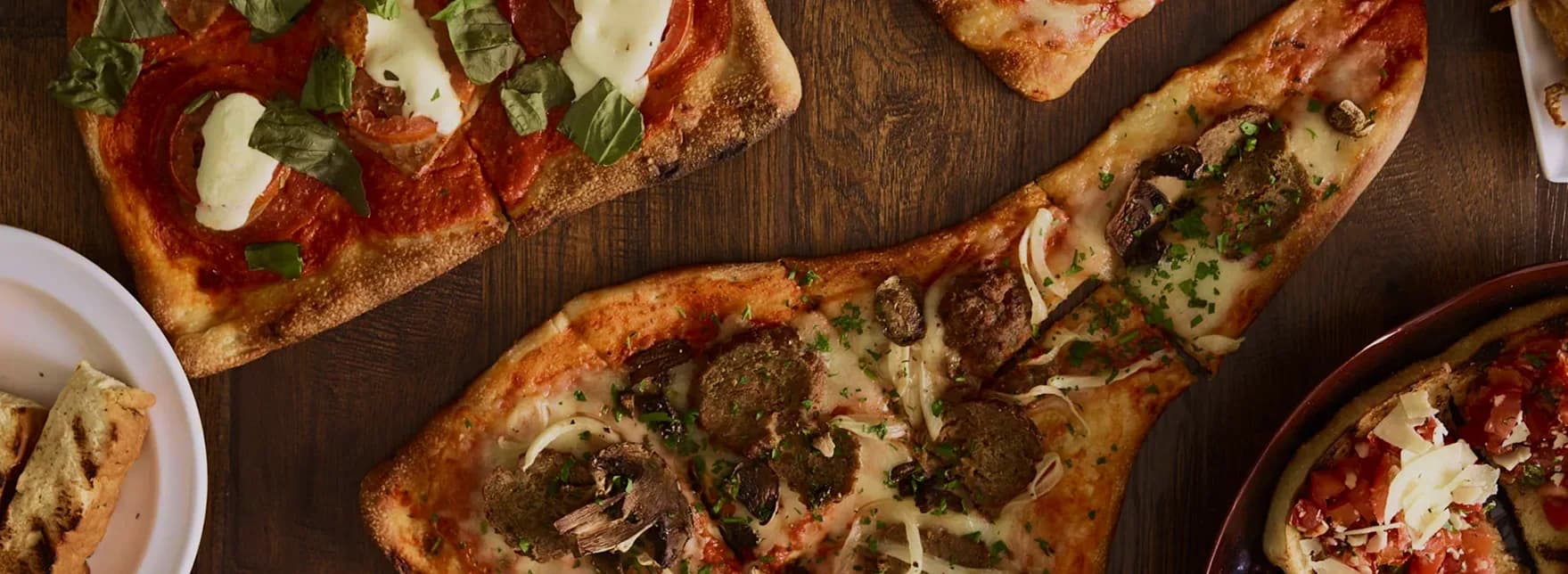 Flatbread pizzas with tomatoes, basil, cheese and mushrooms at Crust Simply Italian
