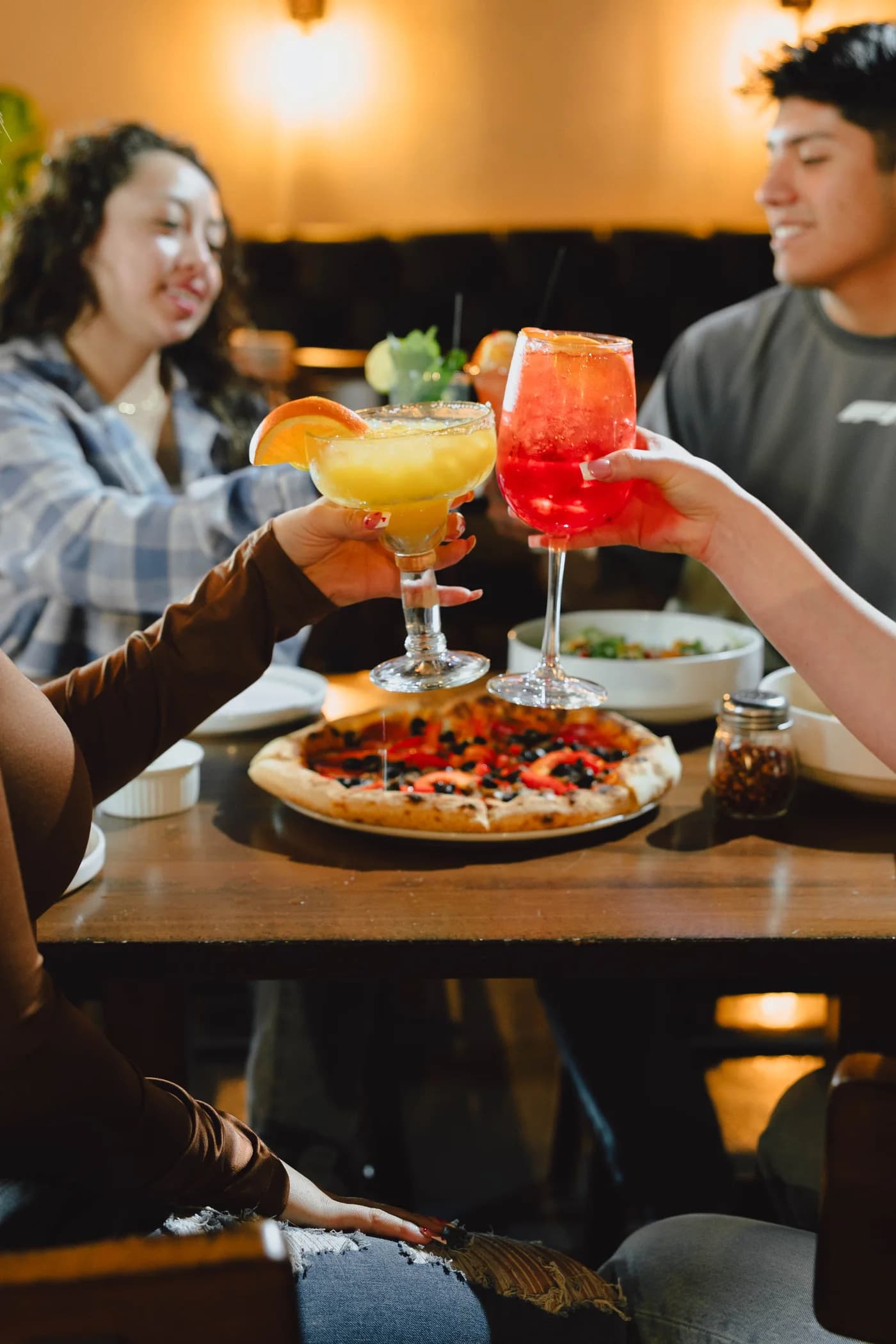 Friends sharing wood-fired pizza and cocktails at Roma 23