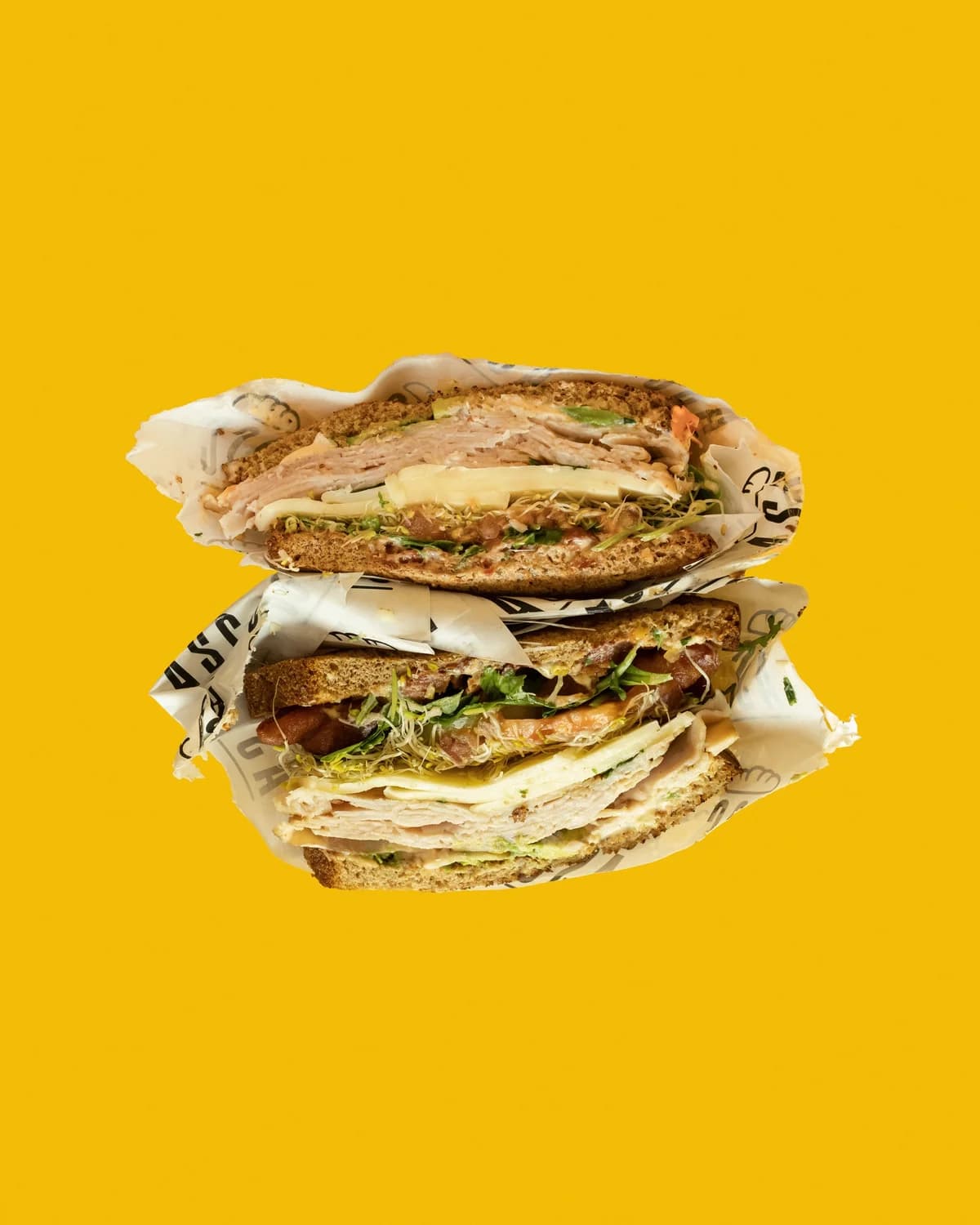 A Sandwich Co. sandwiches stacked on bright yellow with branded wrapping